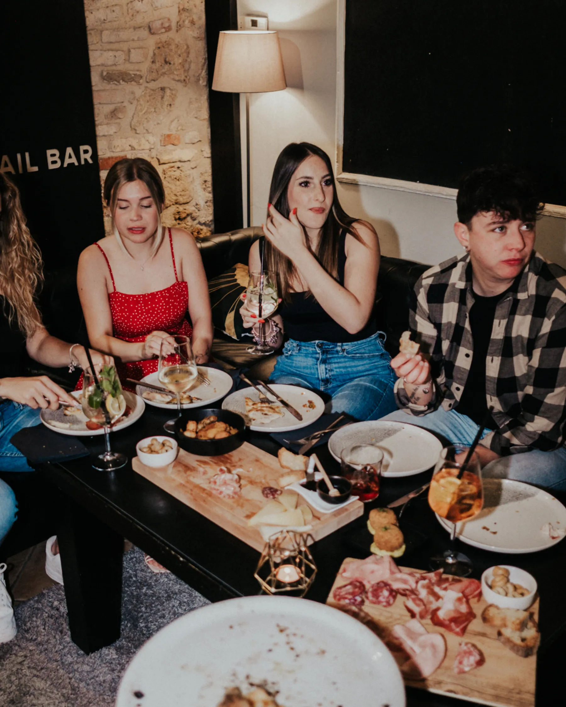 Amici a tavola per l'aperitivo con taglieri e cocktail